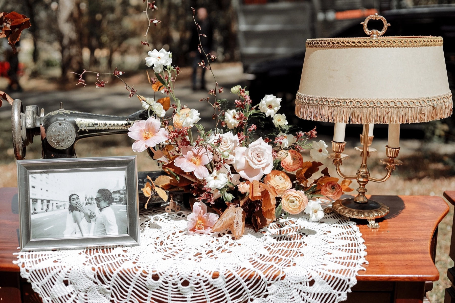 Layered event styling with flowers, framed photographs and a table lamp