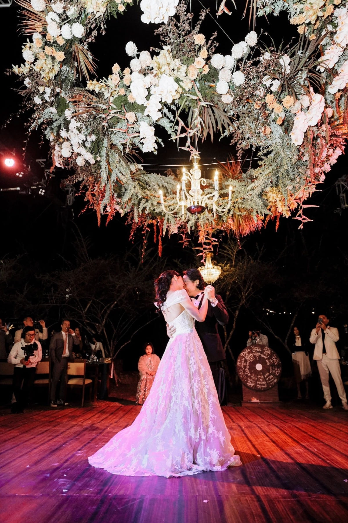 Couple sharing their first dance beneath a floral installation